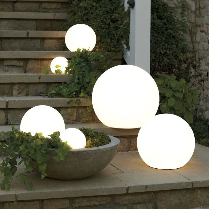 VixxenDecor Spherical Garden Light glowing in a garden bed
